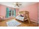 Pink bedroom featuring wooden bunk beds, colorful rug, and ample natural light at 10000 Blossom Dr, Concord, NC 28025