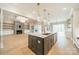 Modern kitchen island with pendant lighting and stainless steel appliances, complemented by an open view of the living room and fireplace at 102 Pecan Cove Ln, Weddington, NC 28104