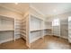 Spacious walk-in closet featuring wood floors, shelving, and a window for natural light at 102 Pecan Cove Ln, Weddington, NC 28104