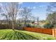 Backyard with a wooden fence, grassy area, and some trees in the distance at 1021 Joselynn Dr, Gastonia, NC 28054