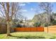 View of the spacious backyard featuring a wood fence, grassy lawn, and mature trees against a bright blue sky at 1021 Joselynn Dr, Gastonia, NC 28054