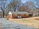Well-maintained brick home with manicured lawn, featuring a gravel driveway and charming exterior details at 10720 Forest Dr, Matthews, NC 28105