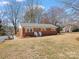 Charming brick home featuring a well-maintained front yard, inviting entryway, and a detached storage shed at 10720 Forest Dr, Matthews, NC 28105