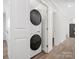 A modern, stacked washer and dryer set neatly tucked away in an alcove with bright white walls at 10720 Forest Dr, Matthews, NC 28105