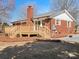 The home's brick exterior and a wooden deck with stairs, complemented by manicured landscaping at 10720 Forest Dr, Matthews, NC 28105