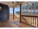 Covered porch with wood flooring and dark stained columns, with a view of the wooded area at 119 Mills Garden Rd, Statesville, NC 28625