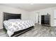 This bedroom features a large bed, a dresser, grey wood flooring, and a door that leads to the bathroom at 16138 Aryshire Green Ct, Charlotte, NC 28273