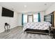 This bedroom features a large bed with grey wood flooring, a TV, a large mirror, and natural light from the windows at 16138 Aryshire Green Ct, Charlotte, NC 28273