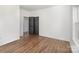 A spacious bedroom with hardwood floors, a window, and black doors leading to a closet at 606 Saint Cloud Dr, Statesville, NC 28625