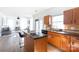 Sunlit kitchen with wooden cabinets, granite countertops, and an island with seating open to the living room at 6420 Tunston Ln, Charlotte, NC 28269