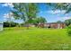 Lush backyard with mature trees, a fire pit, and views of the home's rear exterior at 905 Blalock Dr, Kings Mountain, NC 28086