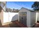 View of outdoor shed with double doors and a brick-paved path along white vinyl privacy fence at 9100 Clancy Pl, Charlotte, NC 28227