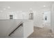 Bright hallway featuring neutral carpet, white walls, and an oak handrail on the staircase at 9512 Coast Laurel Nw Ave # 42, Concord, NC 28027