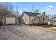 Side view of charming single-story home with gravel driveway, detached garage, and landscaped front yard at 108 S Buckoak St, Stanley, NC 28164