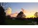 Scenic backyard view featuring a golden sunset, lush green grass, and mature trees at 111 Oakwood Dr, Kings Mountain, NC 28086