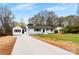 Inviting single-story home with fresh white paint, black shutters, long driveway and complemented by lush trees at 1121 S Edgemont Ave, Gastonia, NC 28054