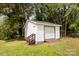Outdoor white shed with garage door and side entrance on a lush green lawn, surrounded by mature trees at 1121 S Edgemont Ave, Gastonia, NC 28054