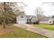 View of the home, with a long driveway, attached two-car garage, well-maintained lawn, and established trees at 1200 Craig Ave, Lancaster, SC 29720