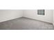 Neutral bedroom boasts soft carpet, white trim, and a bright window showcasing the exterior landscape at 122 Asmodean Ln, Troutman, NC 28166