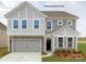 Charming two-story home with stone accents, gray siding, a two-car garage, and well-manicured landscaping at 122 Asmodean Ln, Troutman, NC 28166