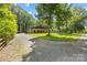 Gravel driveway leading to a charming home surrounded by mature trees at 13124 Lemmond Dr, Matthews, NC 28105