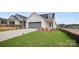 Single-Gathering home with a grey garage door, landscaped yard, and new construction in the background at 1529 Pebble Shore Ln # 164, Belmont, NC 28012
