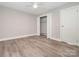 Bedroom with light gray walls, light wood-look floors, and open closet doors at 2628 Park Rd # F, Charlotte, NC 28209