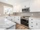 Bright kitchen features white cabinets, stainless steel appliances, and stone countertops at 2628 Park Rd # F, Charlotte, NC 28209