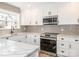 Bright kitchen features white cabinets, stainless steel appliances, and stone countertops at 2628 Park Rd # F, Charlotte, NC 28209