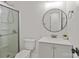 Bathroom with a glass door shower, round mirror, and gray vanity with white sink and a white toilet at 3009 Rockingham Sw Ct, Concord, NC 28025