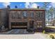 Charming two-story stone home featuring a glass garage door and manicured landscaping at 302 Ambleside Village Ln, Davidson, NC 28036
