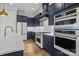 Modern kitchen with custom navy cabinetry, stainless steel appliances, and quartz countertops with a farmhouse sink at 302 Ambleside Village Ln, Davidson, NC 28036