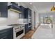 Gourmet kitchen with stainless steel appliances, navy blue cabinets, and a view into the adjacent dining area at 302 Ambleside Village Ln, Davidson, NC 28036
