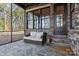 Cozy outdoor seating area with stone floors, stone facade, screened in porch, and wooded views at 302 Ambleside Village Ln, Davidson, NC 28036