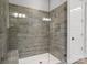 Walk-in shower features wood look tile surround, glass door, and white hexagon tile flooring at 302 Ambleside Village Ln, Davidson, NC 28036