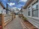 View of a gravel driveway between homes, bordered by a wooden fence and brick pavers at 324 Westwood Ave, Charlotte, NC 28203