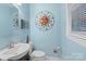 Powder room with painted blue walls, a decorative sunburst wall decoration, and a toilet at 3714 Conway Ave, Charlotte, NC 28209
