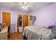 Bedroom with hardwood floors, two closets, a desk, purple walls and ceiling fan at 3714 Conway Ave, Charlotte, NC 28209