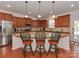 A kitchen island with granite countertops and brown cabinetry offers seating for three beneath pendant lights at 4856 Pepper Dr, Harrisburg, NC 28075