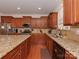 A kitchen with granite countertops, wooden cabinets, stainless appliances, and wood floors provides style and functionality at 4856 Pepper Dr, Harrisburg, NC 28075