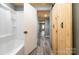 View of a bathroom with white shower leading to a hallway with wood plank ceiling at 520 Rogers St, Albemarle, NC 28001