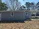 Gray house featuring a mix of new windows and a carport, set against a natural backdrop at 811 Sanford St, Marshville, NC 28103