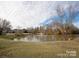 Scenic view of community pond with fountain, surrounded by trees and lush lawns and a blue sky with wispy clouds at 9423 Belmont Ln, Marvin, NC 28173