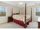 Bedroom with carpet flooring, large four-poster bed with floral comforter, two windows, and side tables at 9601 Whitethorn Dr, Charlotte, NC 28277