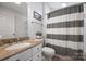 Well-maintained bathroom showcases a granite vanity, toilet, and a shower with a stylish striped curtain at 9627 Baileywick Rd, Charlotte, NC 28277