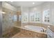 Bright bathroom with tub, stand up shower with glass enclosure, and a window with shuttered blinds at 9627 Baileywick Rd, Charlotte, NC 28277