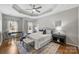 Comfortable main bedroom with tray ceiling, ceiling fan, ample natural light, and a calming color palette at 9627 Baileywick Rd, Charlotte, NC 28277