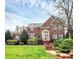 Elegant two-story brick home with manicured lawn and charming architectural details at 9800 Deer Brook Ln, Charlotte, NC 28210