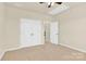 Bedroom features neutral carpet, a ceiling fan, and a double-door closet at 982 Old Trace Nw Rd, Concord, NC 28027