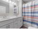 Bathroom featuring a double sink vanity, modern faucets, and large shower with a colorful curtain at 105 S York St, Lancaster, SC 29720